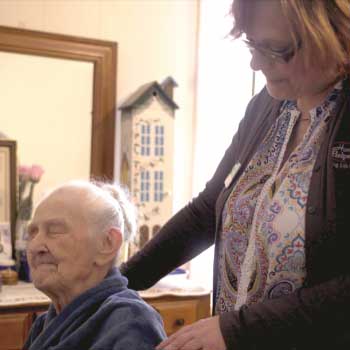 Caretaker wrapping blanket around a senior